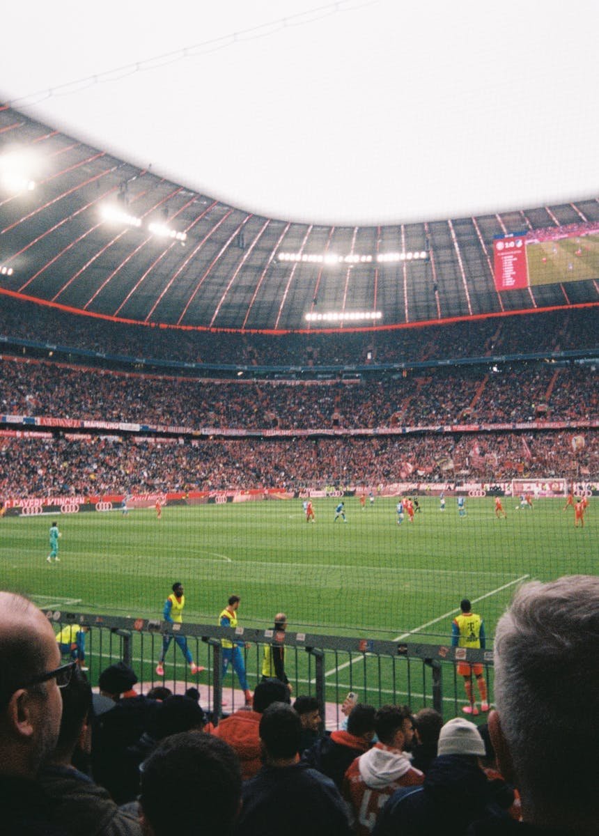 Vibrant crowd enjoying a live soccer game in a large, illuminated stadium.