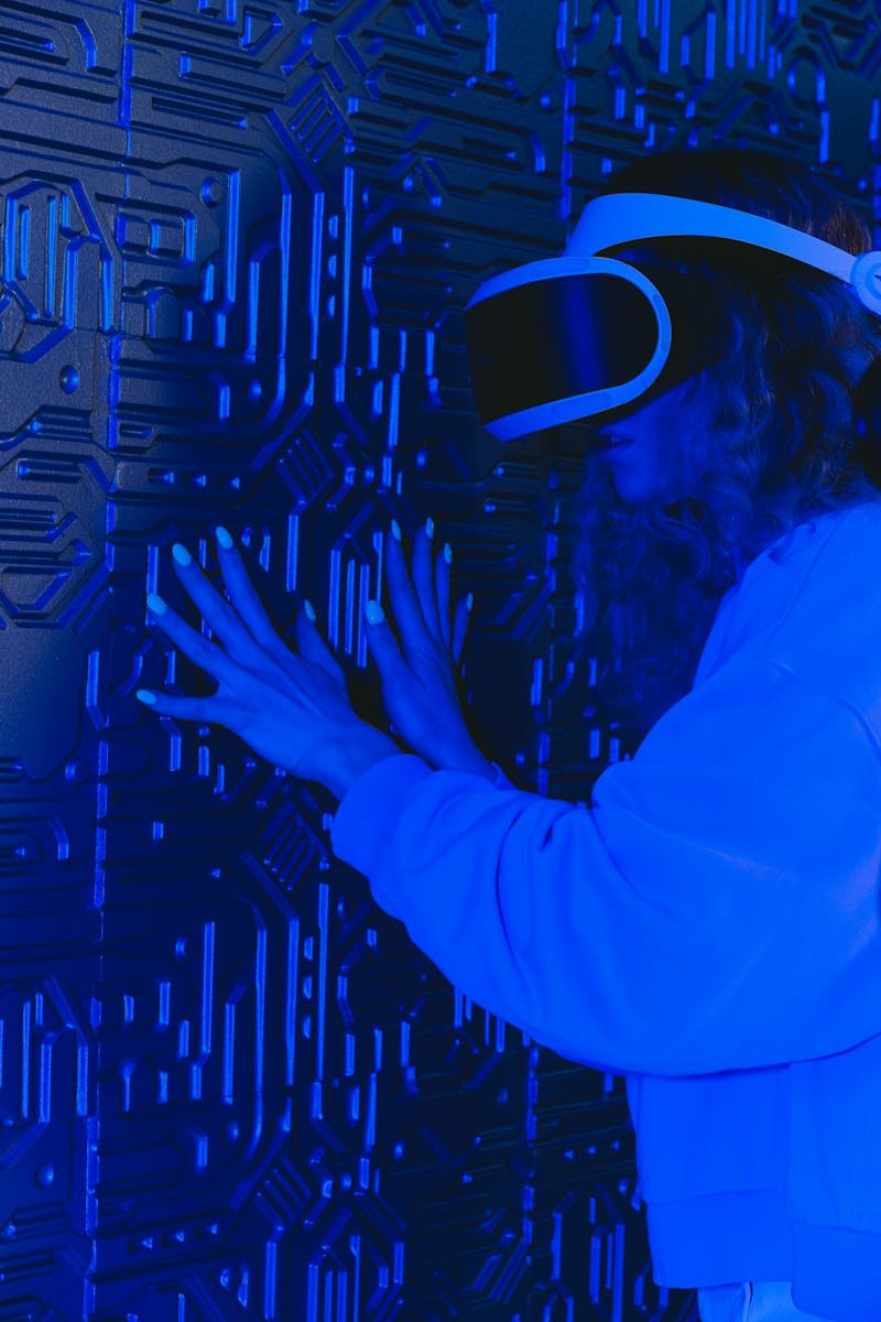 A woman with a VR headset interacts with a textured wall under blue lighting.